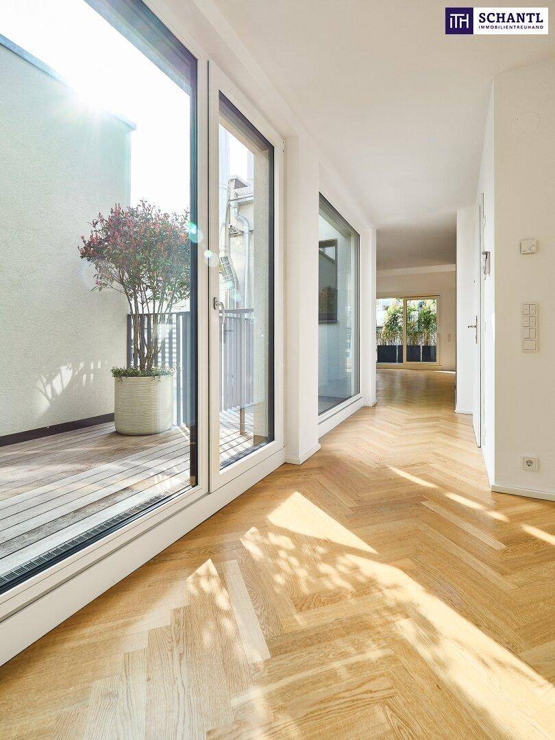 Lichtdurchfluteter Raum mit Fischgrätparkett und Zugang zu einem sonnigen Balkon.
