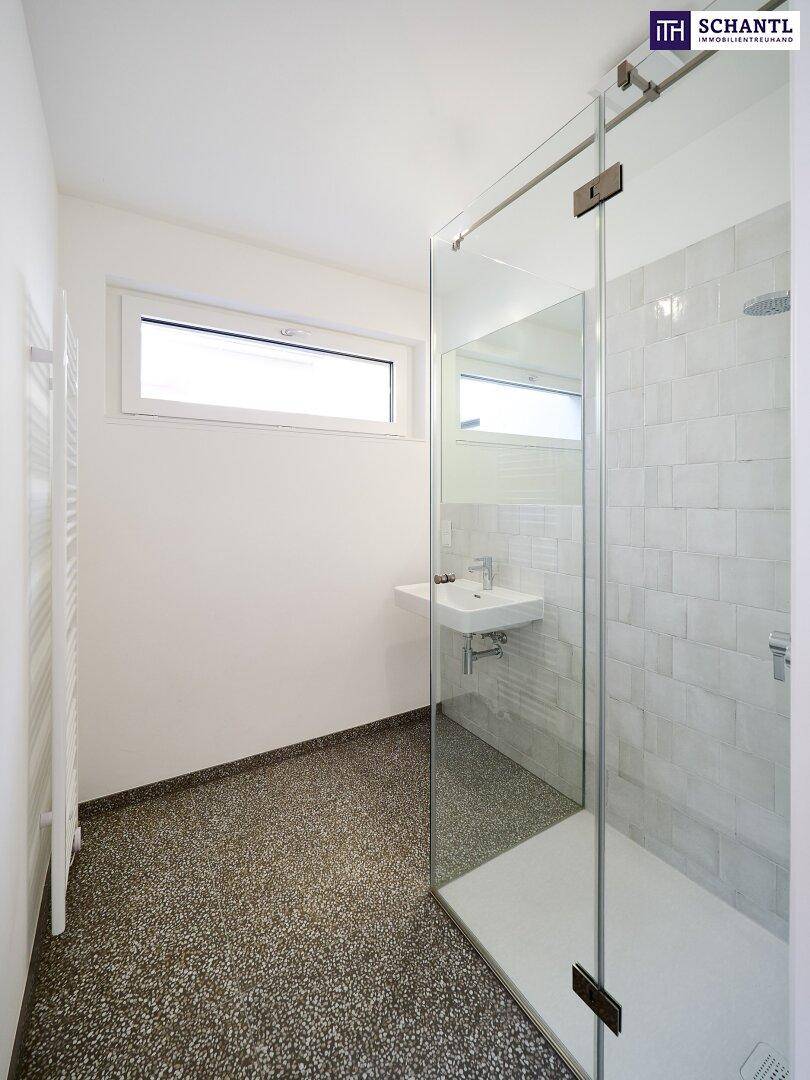 Helles Badezimmer mit Fenster, begehbarer Dusche und modernem Waschbecken.