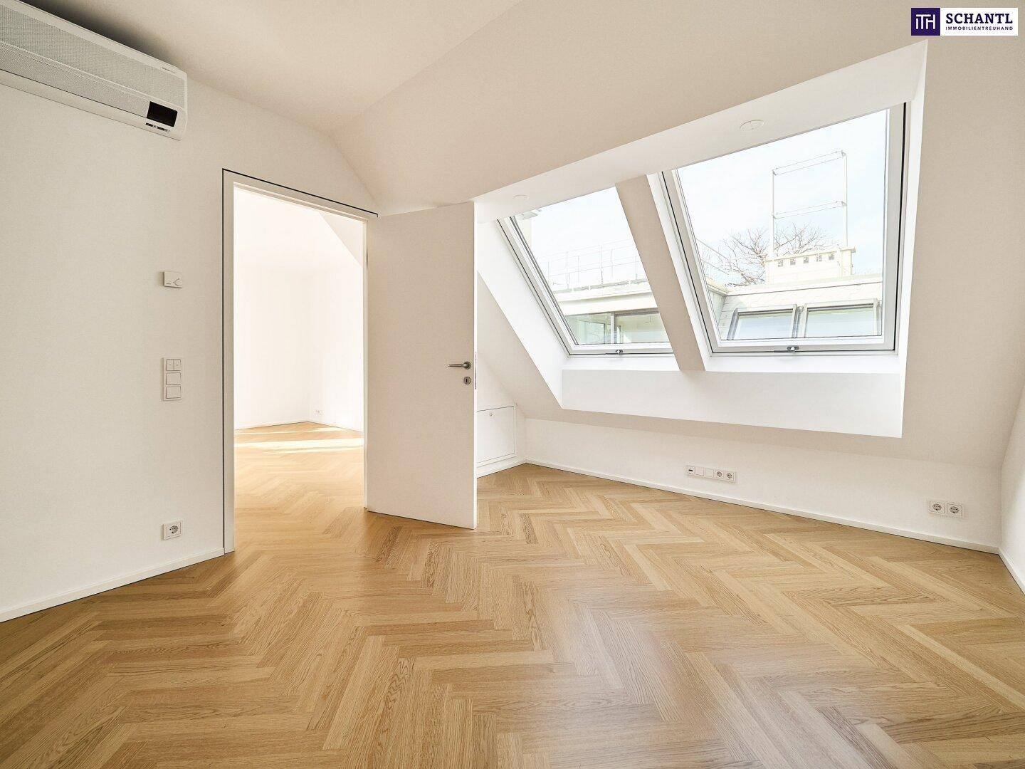 Dachgeschosszimmer mit Fischgrätparkett, Dachfenstern und Klimaanlage für angenehmes Wohnklima.