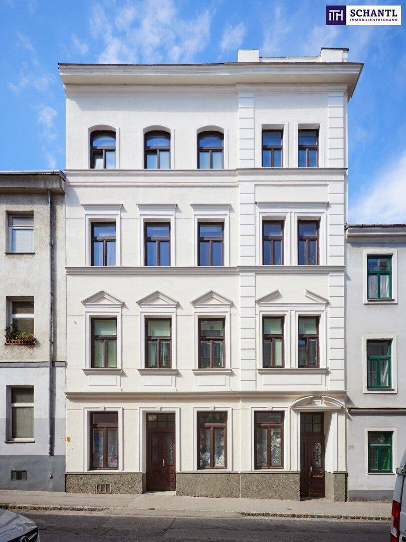 Klassische Altbaufassade mit eleganten Fenstern und architektonischen Details unter blauem Himmel.