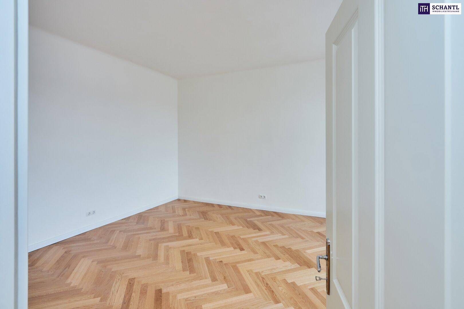 Geräumiges Zimmer mit hellem Fischgrätparkett, weißen Wänden und viel Tageslicht.