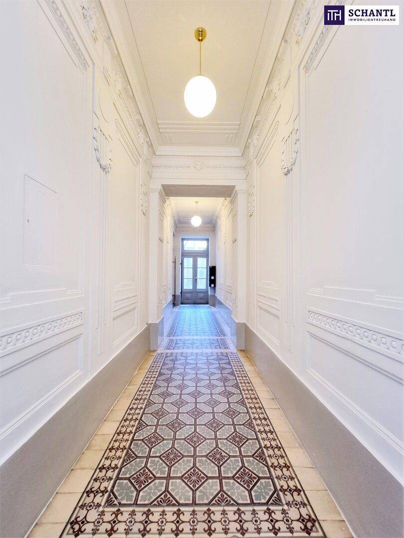 Eleganter Flur mit kunstvollen Stuckverzierungen, gemusterten Fliesen und hoher Decke.
