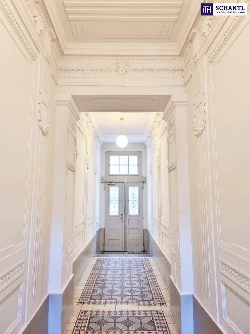 Eleganter Flur mit kunstvollen Stuckverzierungen, gemusterten Fliesen und hoher Decke.