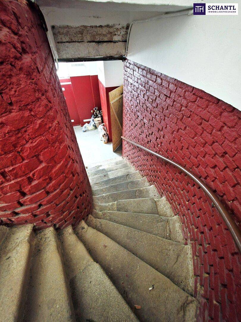 Enge Wendeltreppe im Keller mit roten Ziegelwänden und Metallhandlauf.