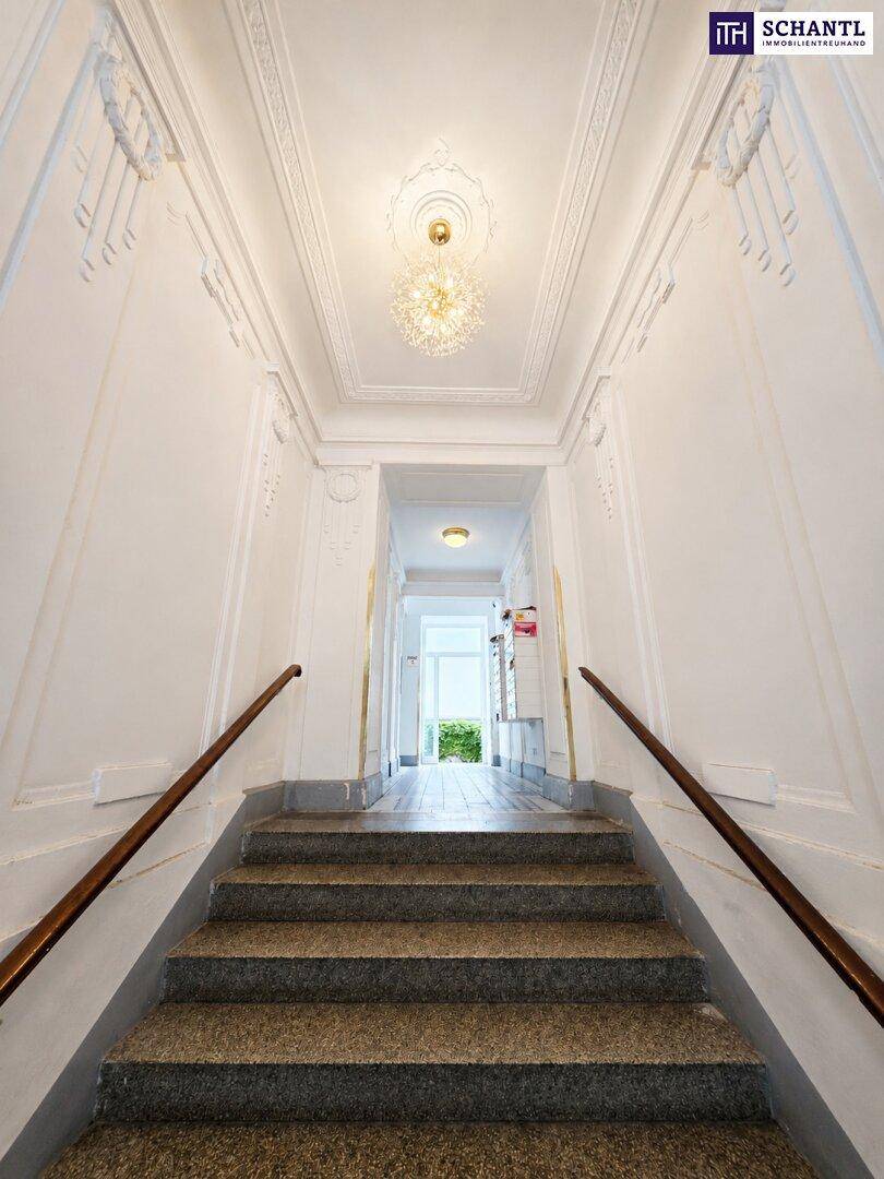 Elegantes Treppenhaus mit Stuckdecken, Marmorstufen und einem Kronleuchter.