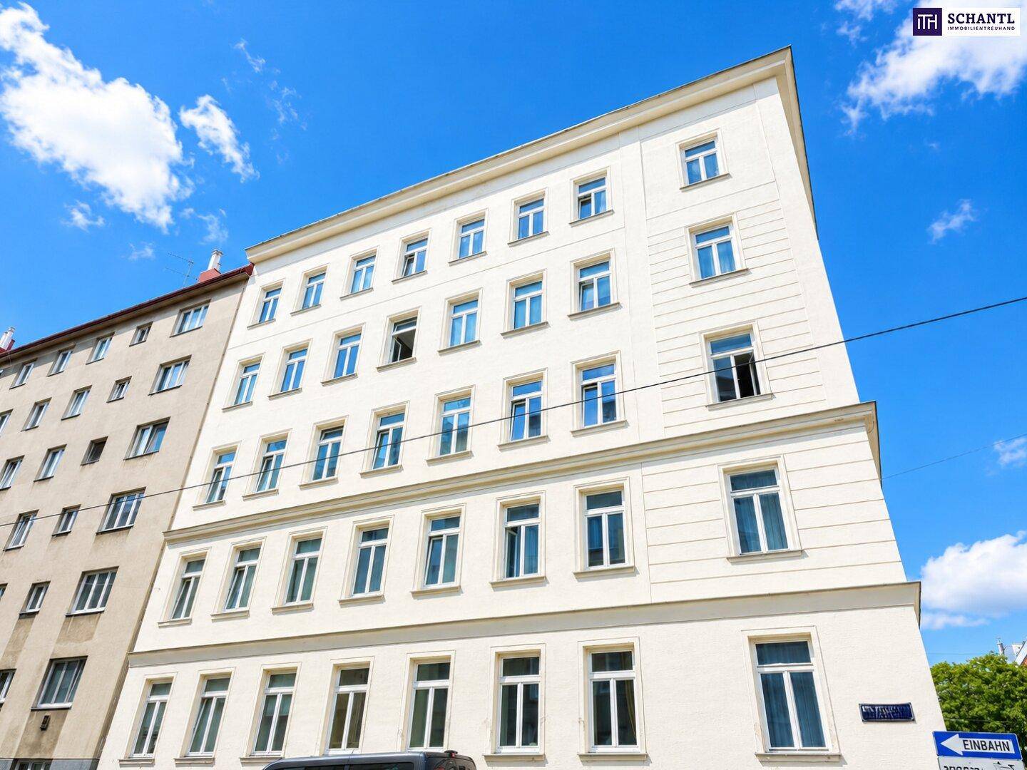 Klassisches Wohnhaus mit weißer Fassade und zahlreichen Fenstern in urbaner Umgebung.