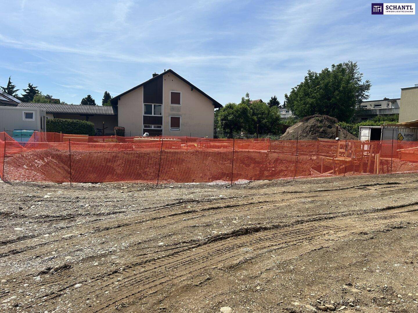 Übersicht der Baustelle mit ausgehobener Grube und angrenzenden Gebäuden.