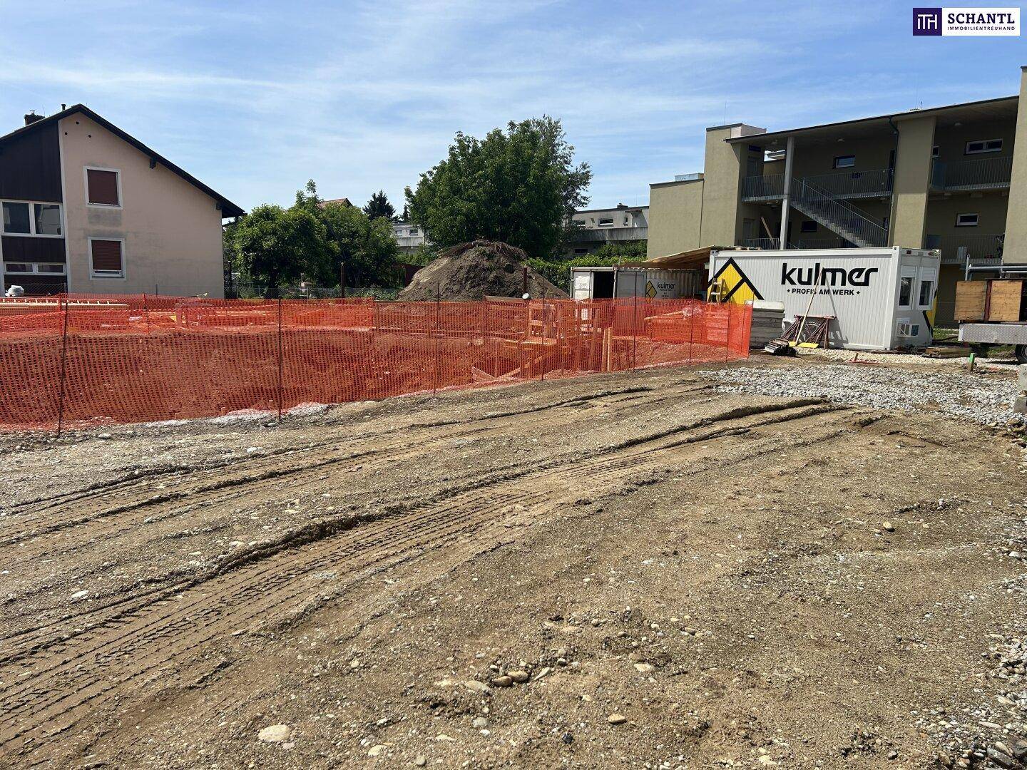 Baustelle mit Baucontainern und vorbereitetem Baugrund für ein neues Gebäude.