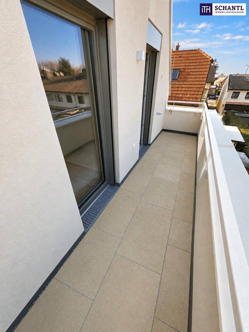 Langer, schmaler Balkon mit hellen Fliesen und Blick auf die Nachbarschaft.