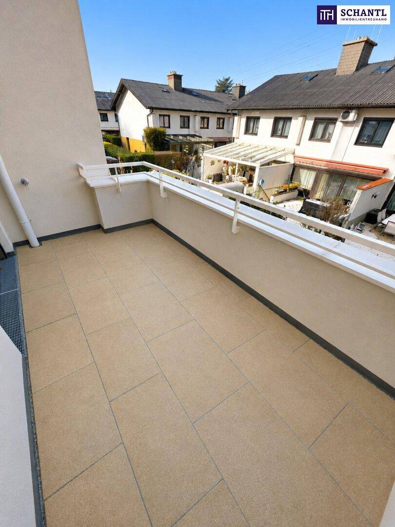 Geräumiger Balkon mit hellen Fliesen und Blick auf die umliegenden Wohnhäuser.