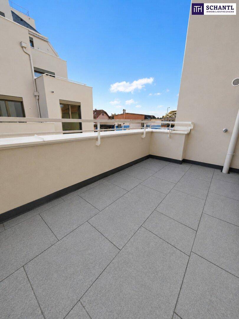 Sonniger Balkon mit grauen Bodenfliesen und weißem Geländer, bietet einen weiten Blick in die Ferne.