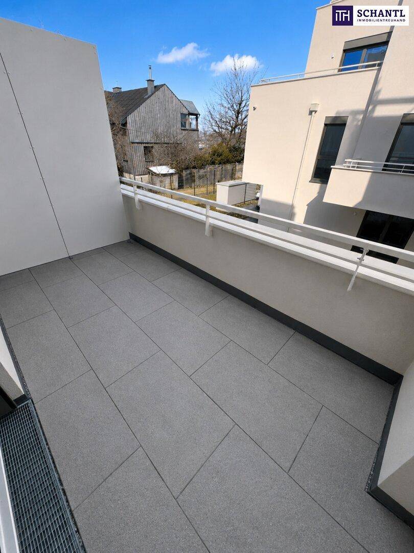 Heller Balkon mit modernen grauen Fliesen und weißem Geländer, bietet einen Blick auf die Umgebung.
