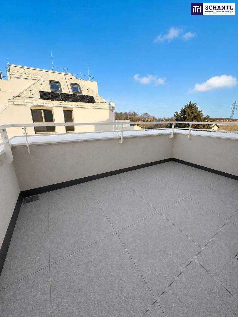 Geräumiger Balkon mit modernen grauen Fliesen und klarem Himmel im Hintergrund.