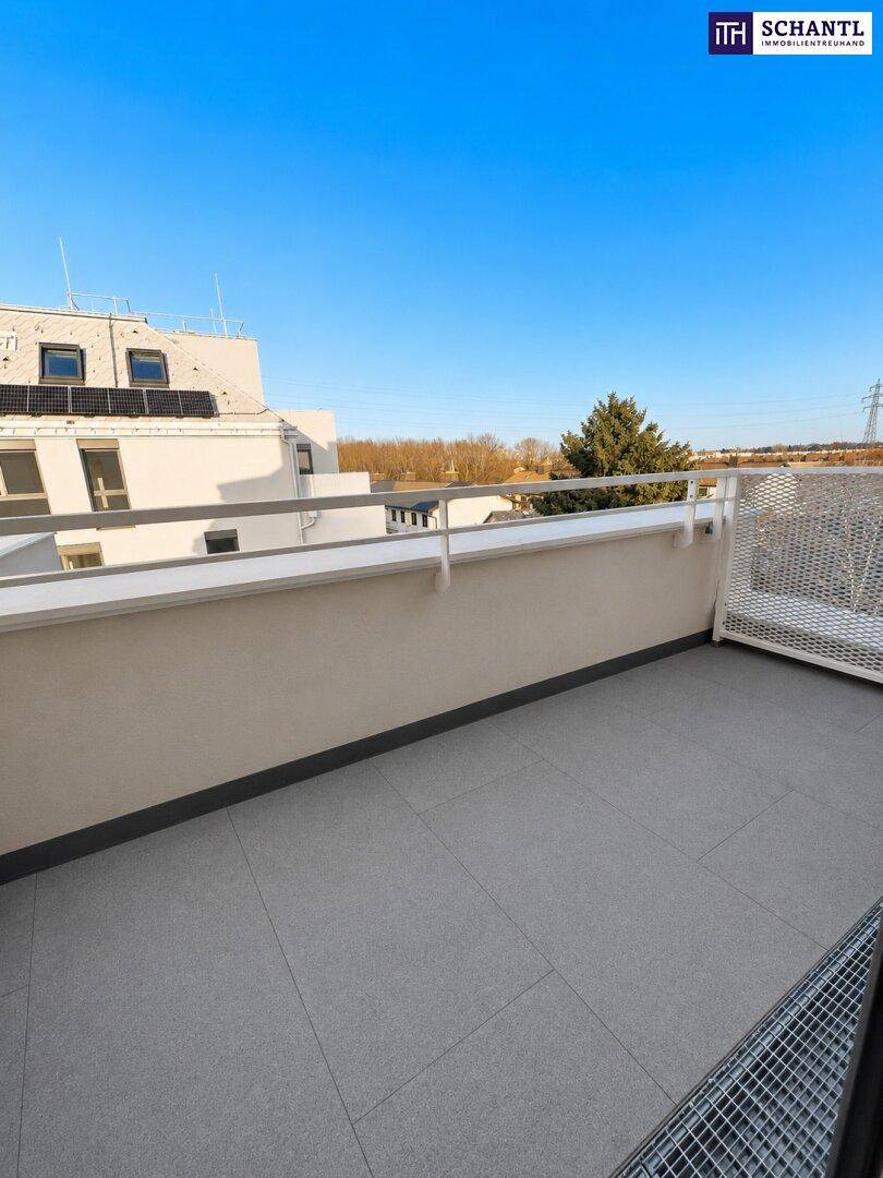 Heller Balkon mit grauen Fliesen und weißem Geländer, bietet einen weiten Blick.