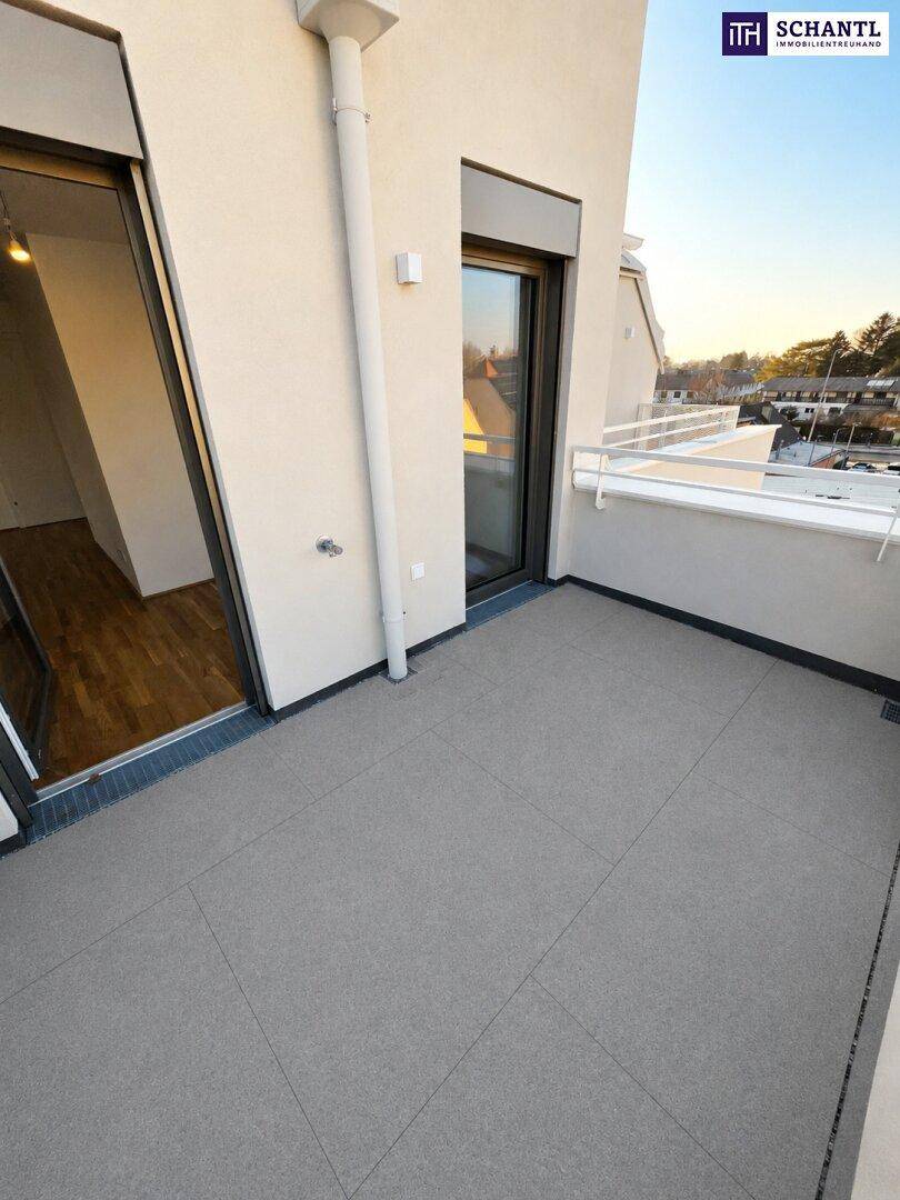 Geräumiger Balkon mit grauen Fliesen und Zugang zum Innenbereich, sonnige Atmosphäre.