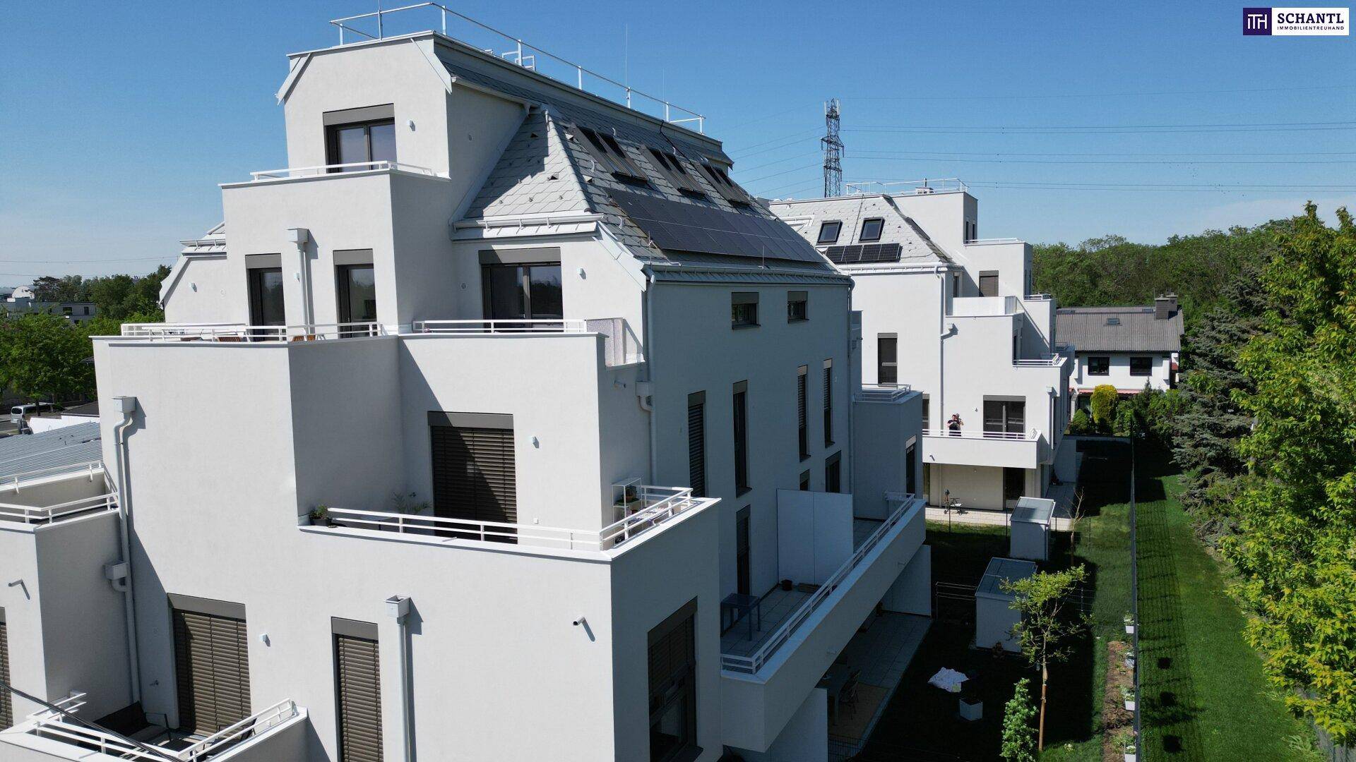 Seitenansicht eines modernen Wohngebäudes mit mehreren Balkonen und Photovoltaik auf dem Dach.