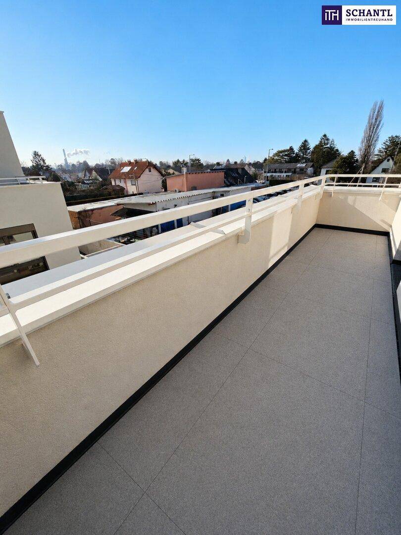 Geräumiger Balkon mit hellen Fliesen und Blick auf die umliegende Bebauung.