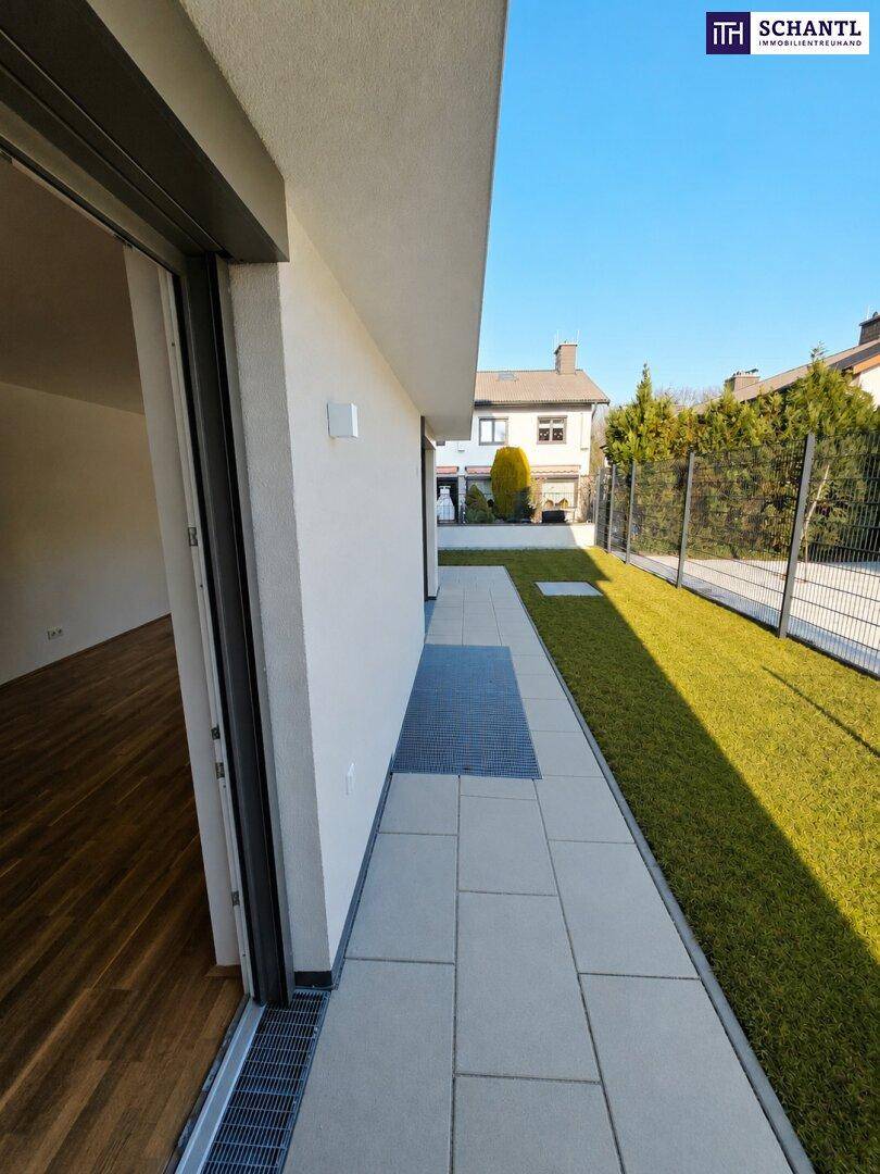 Heller Terrassenbereich mit Entwässerungsrinne und direktem Zugang zu einem Zimmer mit Holzfußboden.