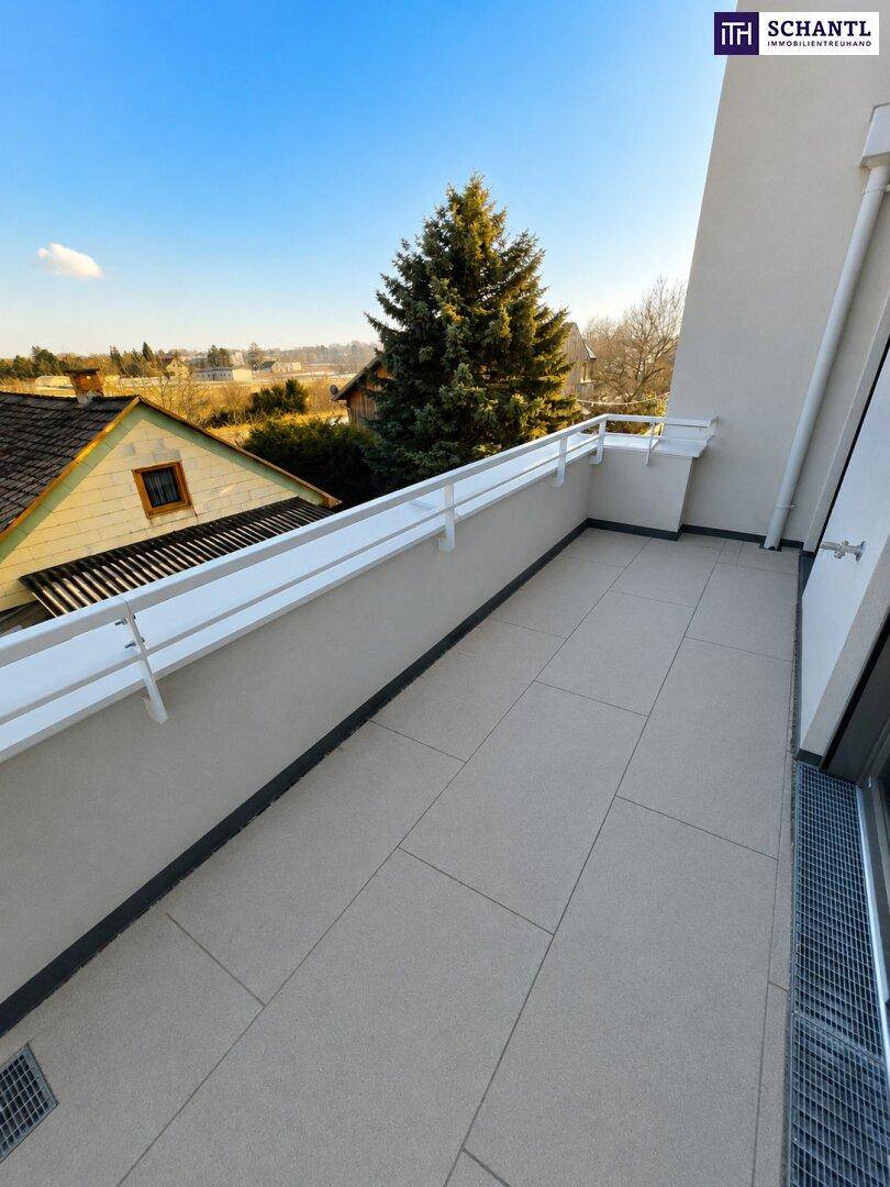Sonniger Balkon mit Fliesenboden und Blick auf Bäume und die Umgebung.