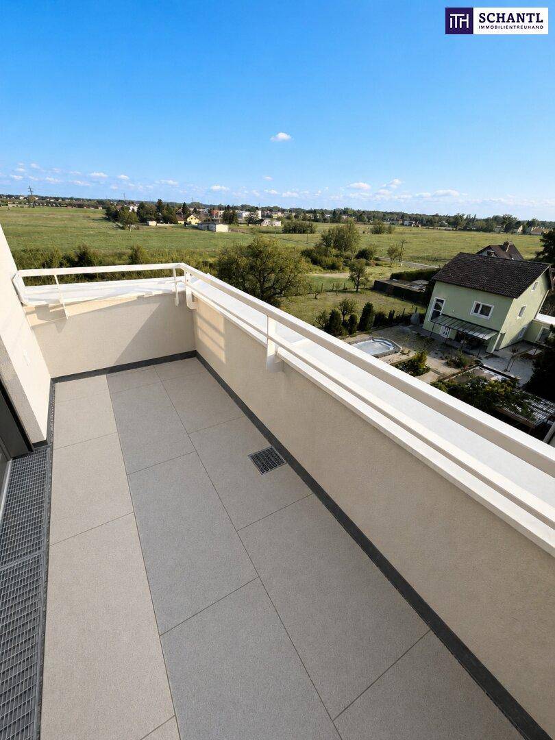 Geräumiger Balkon mit Fliesenboden und weitem Blick ins Grüne und auf die Landschaft.