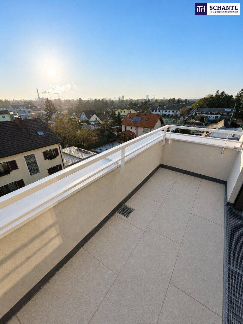 Heller Balkon mit Fliesenboden und Blick auf die umliegende Wohnbebauung bei Sonnenlicht.