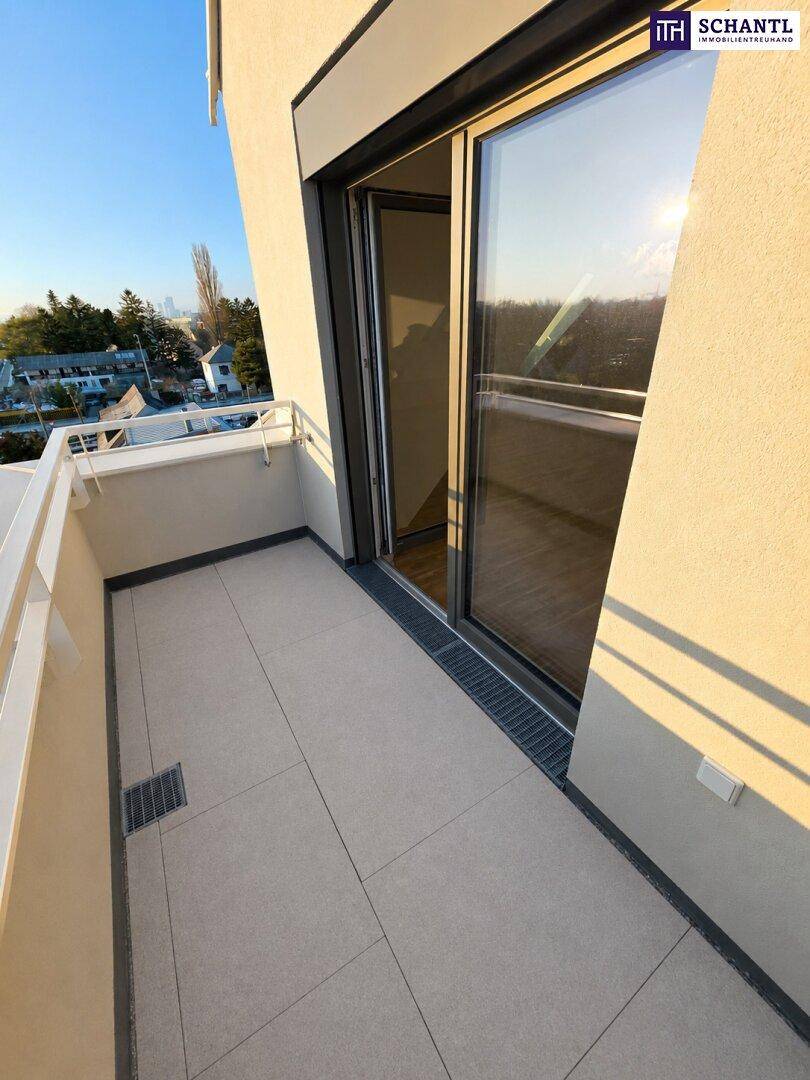 Heller Balkon mit Fliesenboden und Zugang zu einem Innenraum durch eine große Glasschiebetür.