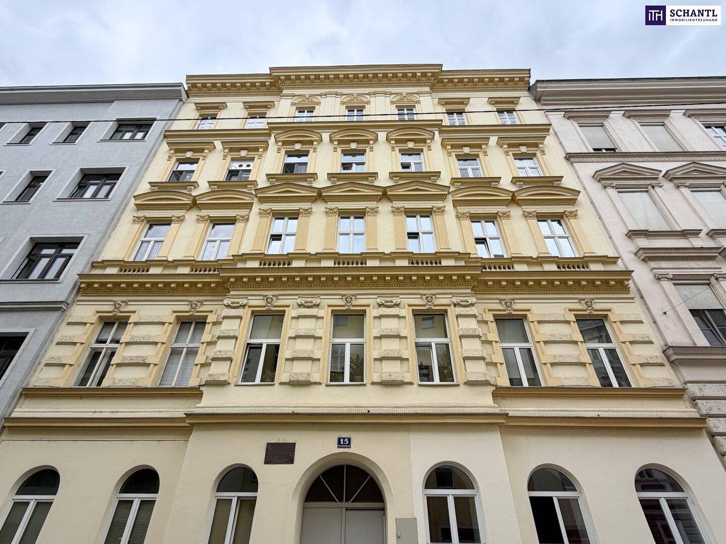 Historische Fassade eines Mehrfamilienhauses mit vielen Fenstern und klassischer Architektur.