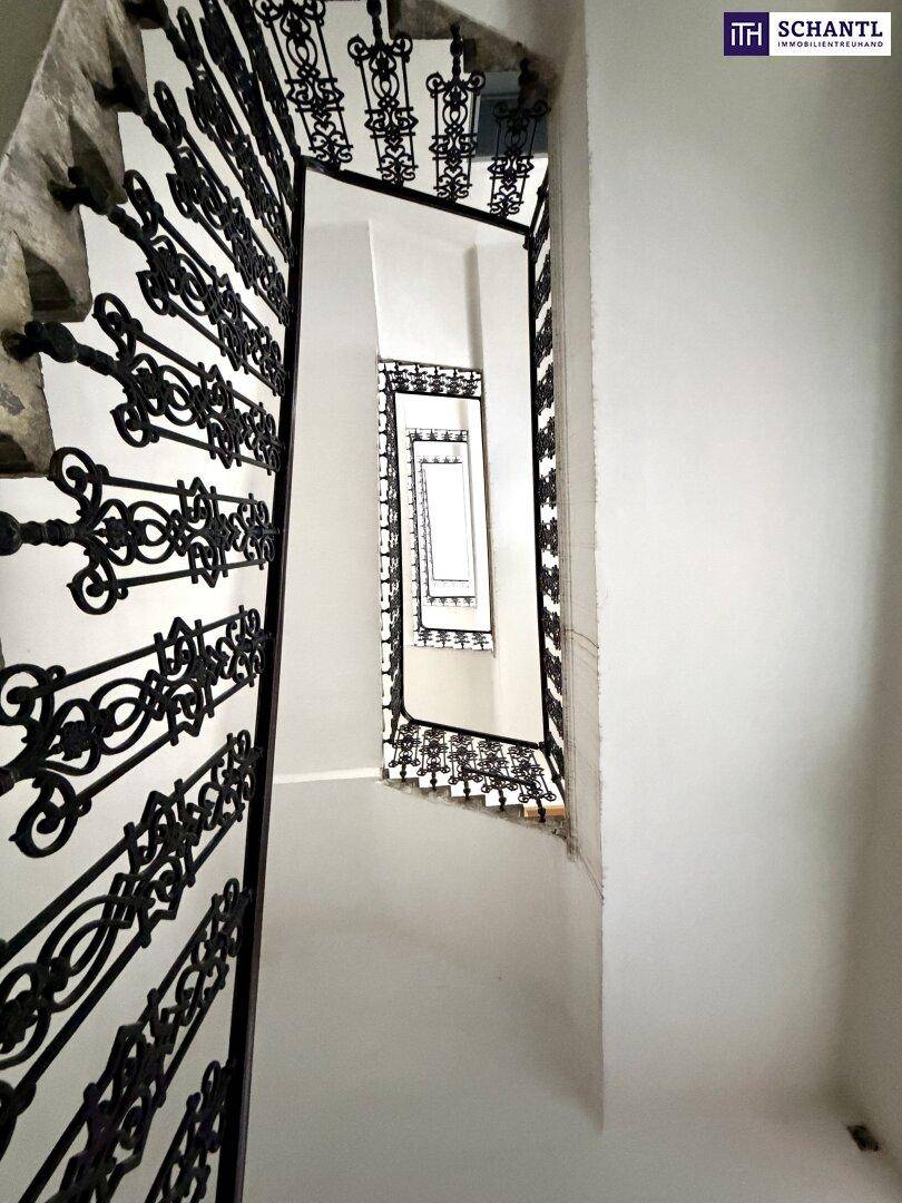 Elegantes Treppenhaus mit kunstvollem schmiedeeisernem Geländer, das sich spiralförmig nach oben windet.