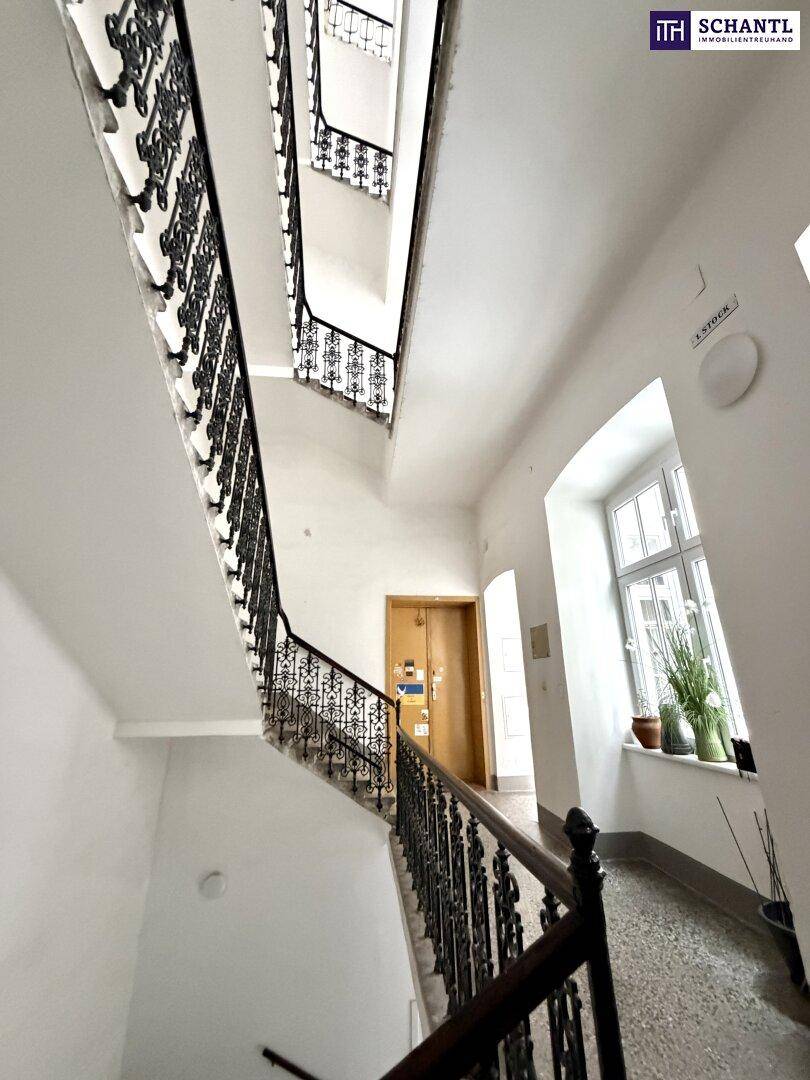 Historisches Treppenhaus mit schmiedeeisernem Geländer und hohen Decken, gut erhalten und gepflegt.