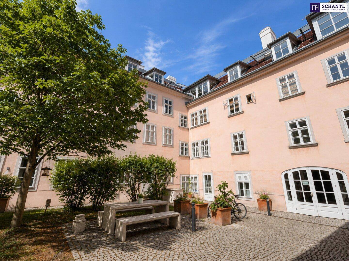 Gemütlicher Innenhof mit Sitzgelegenheiten, Bäumen und Pflanzen, ideal zum Entspannen im Freien.