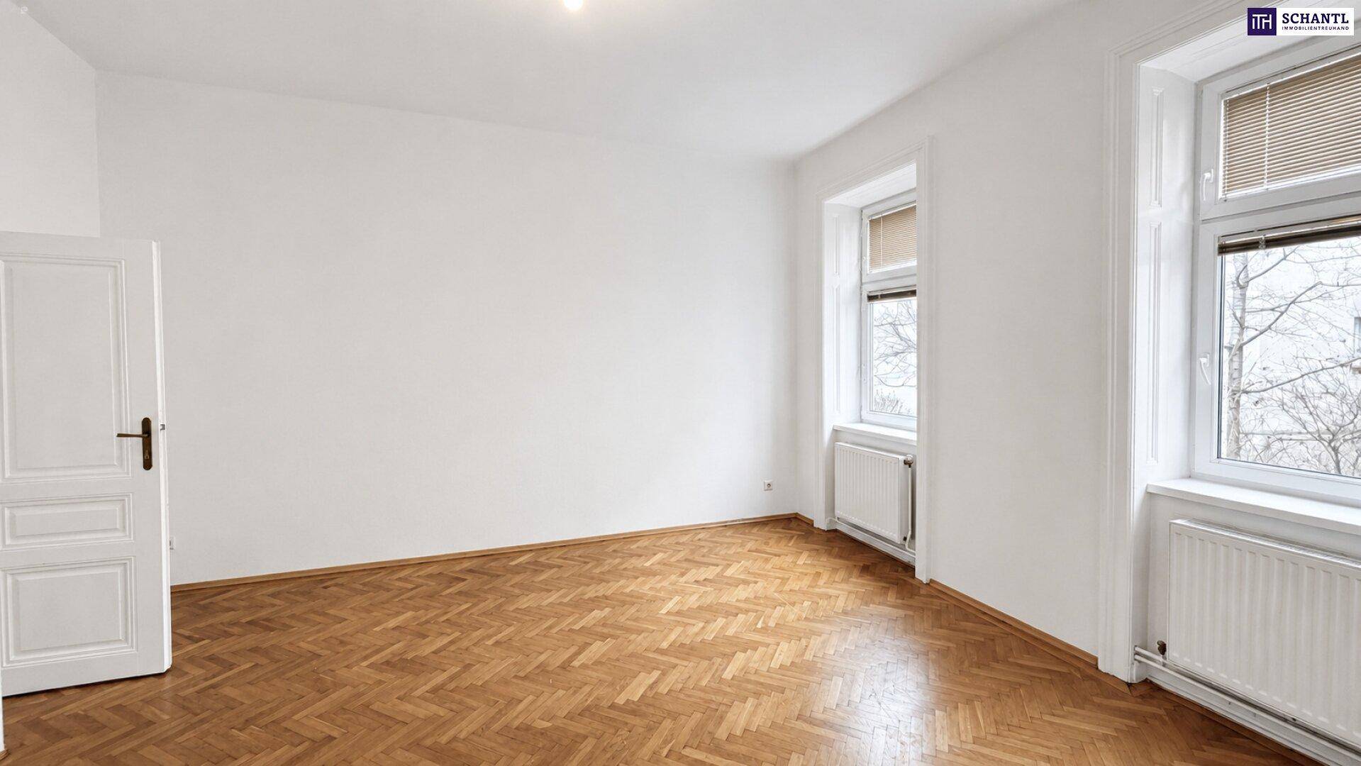 Helles Zimmer mit zwei Fenstern, Fischgrätparkett und weißen Wänden, ideal für Wohnzwecke.