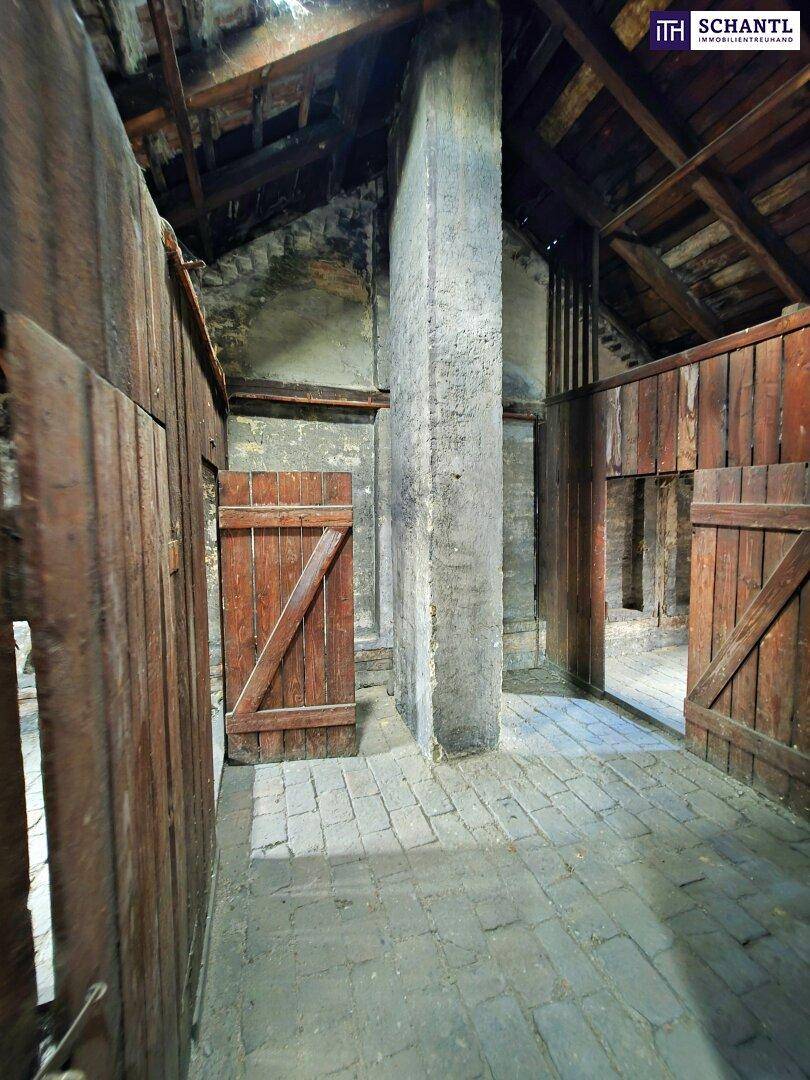 Dachboden mit robusten Holzbalken, Ziegelboden und rustikalen Holztüren.