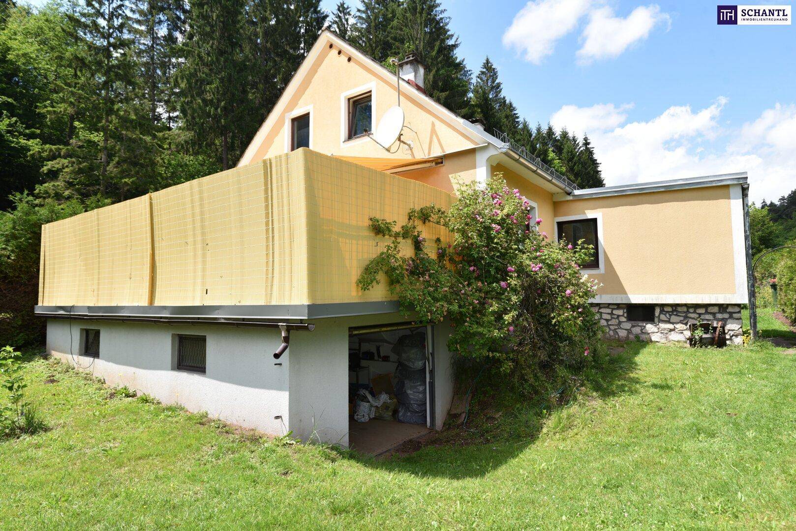 Seitenansicht des Hauses mit gelber Fassade, Balkon und integrierter Garage im Untergeschoss.