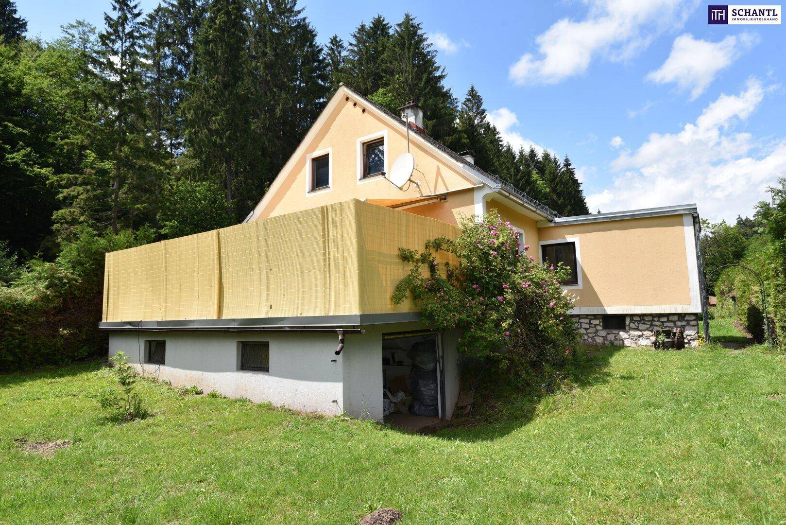 Hausansicht mit gelber Fassade, Balkon und integrierter Garage, umgeben von grünem Rasen.