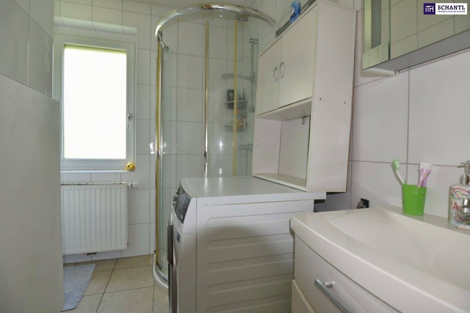 Helles Badezimmer mit Dusche, Waschbecken und Fenster, ausgestattet mit einer Waschmaschine.