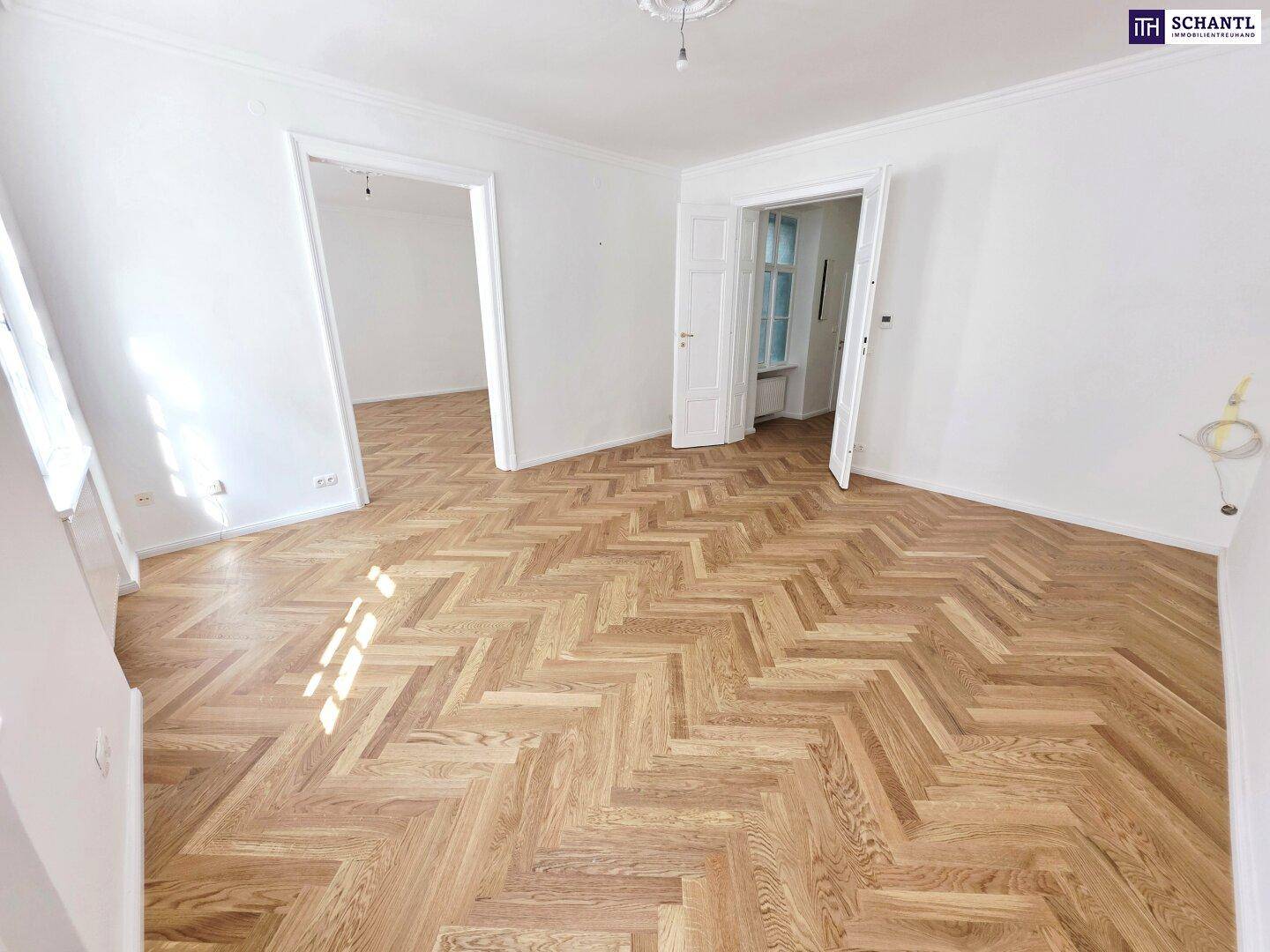 Geräumiges Zimmer mit klassischem Fischgrätparkett und hohen Decken, ideal für Wohn- oder Schlafbereich.