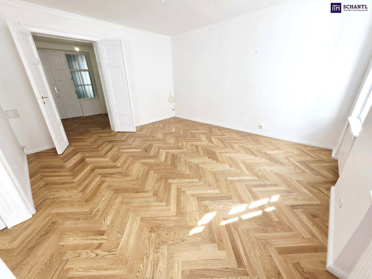 Heller Raum mit elegantem Fischgrätparkett und hohen Decken, der vielseitig genutzt werden kann.