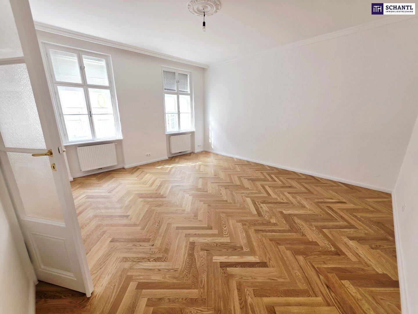 Geräumiges Zimmer mit Fischgrätparkett, hohen Decken und zwei großen Fenstern, vielseitig nutzbar.