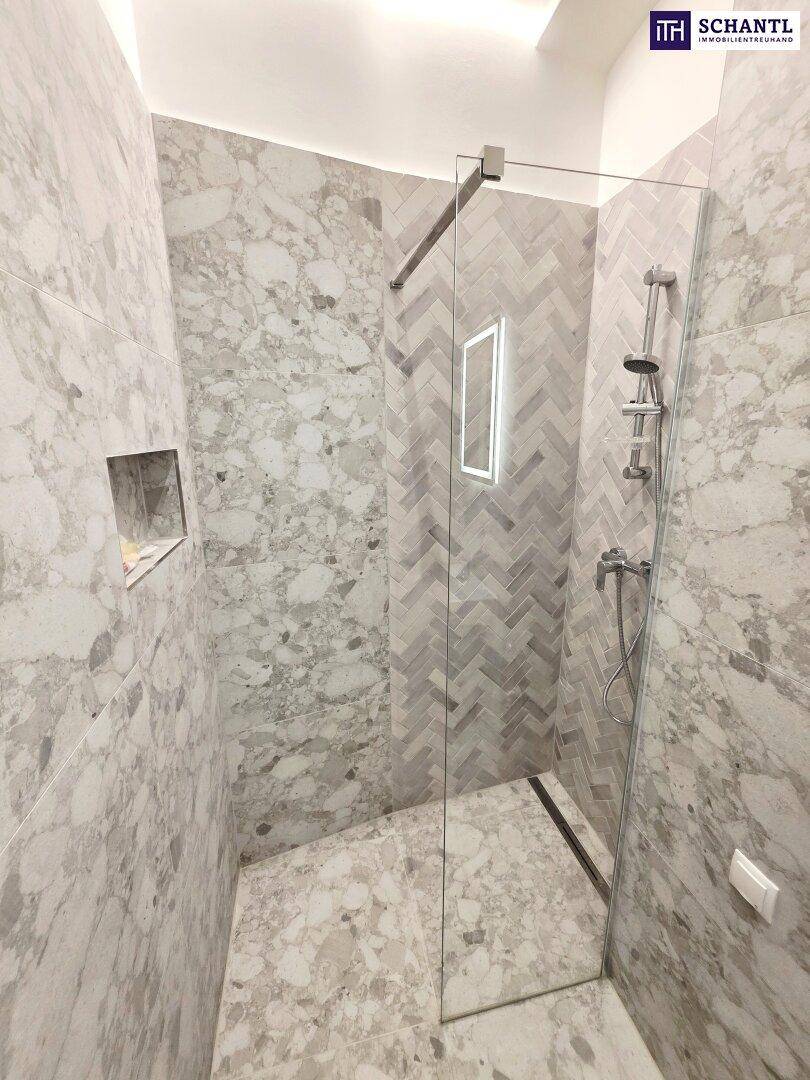 Ebenerdige Dusche mit Glasabtrennung und modernen grauen Fliesen im Fischgrätmuster.