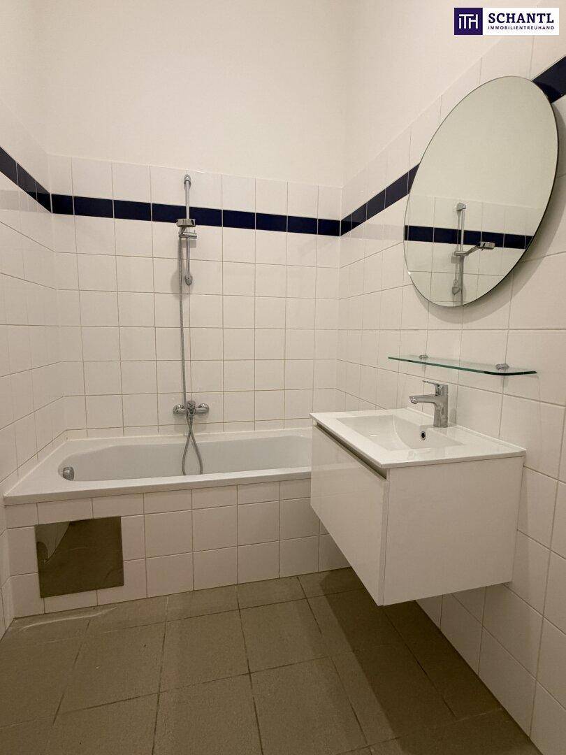 Helles Badezimmer mit weiß gefliesten Wänden, Badewanne mit Duschfunktion und modernem Waschtisch.