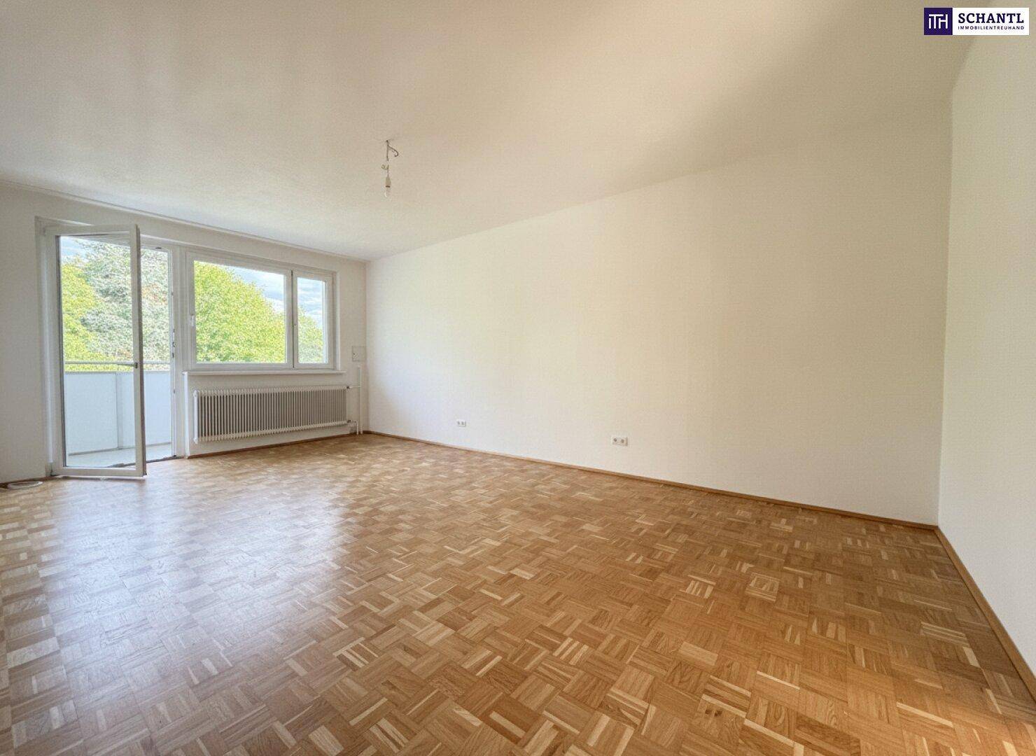 Helles Zimmer mit Parkettboden und Zugang zu einem Balkon, ideal als Wohn- oder Schlafzimmer.