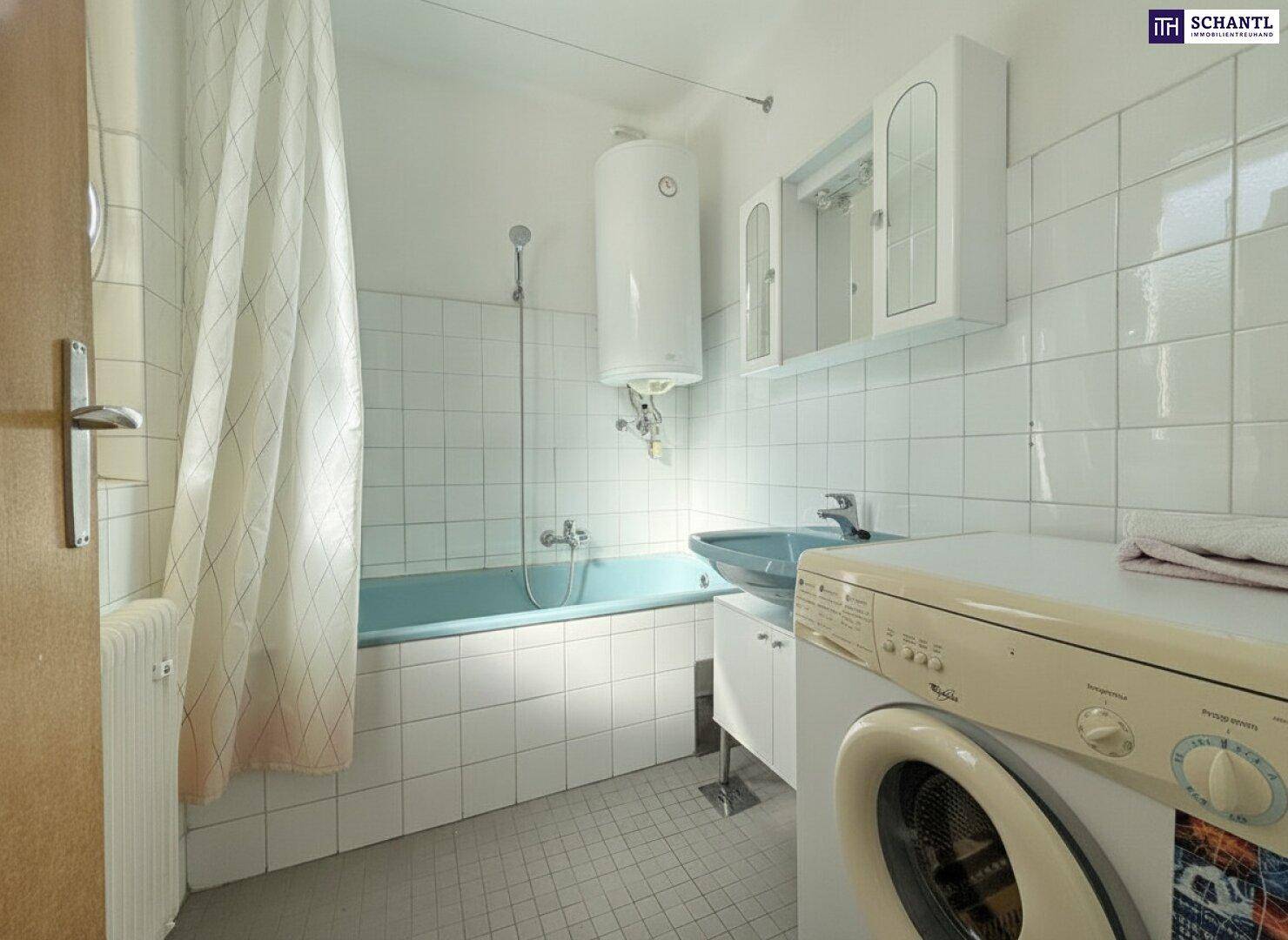 Badezimmer mit blauer Badewanne, weißen Fliesen und einer Waschmaschine, funktional eingerichtet.