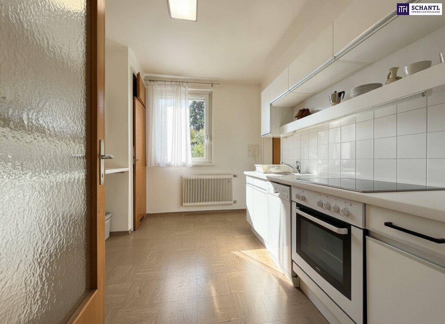 Funktionale Küche mit weißen Schränken, integriertem Backofen und einem Fenster für Tageslicht.