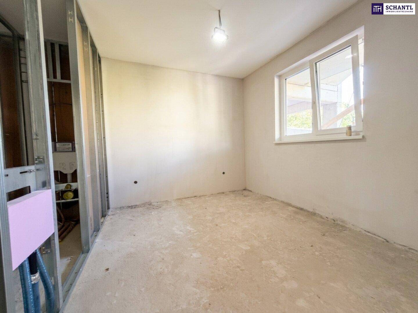 Unfertiger Raum mit Fenster und vorbereiteten Wänden für den Innenausbau.