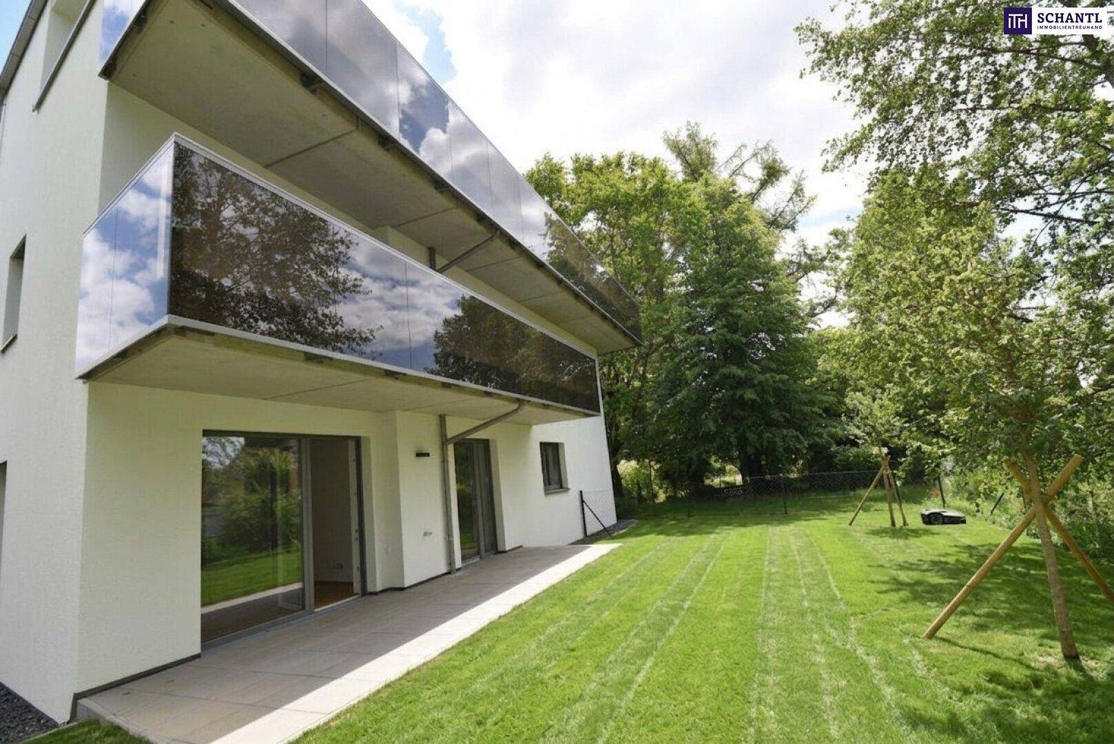 Moderne Gebäudefassade mit Glasbalkonen und einem grünen Gartenbereich mit Schaukel.