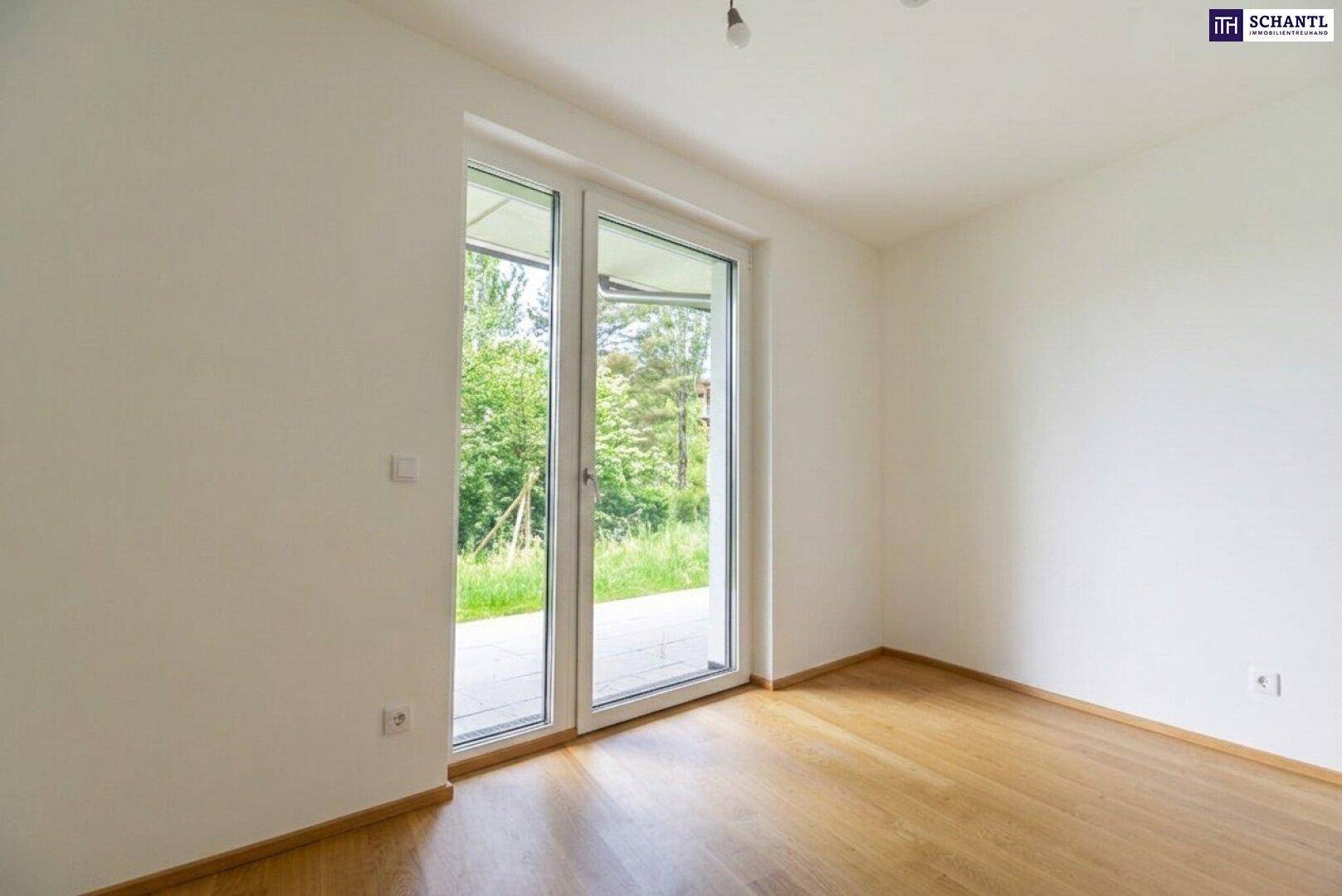 Lichtdurchflutetes Zimmer mit Holzboden und großen Schiebetüren zum Außenbereich.