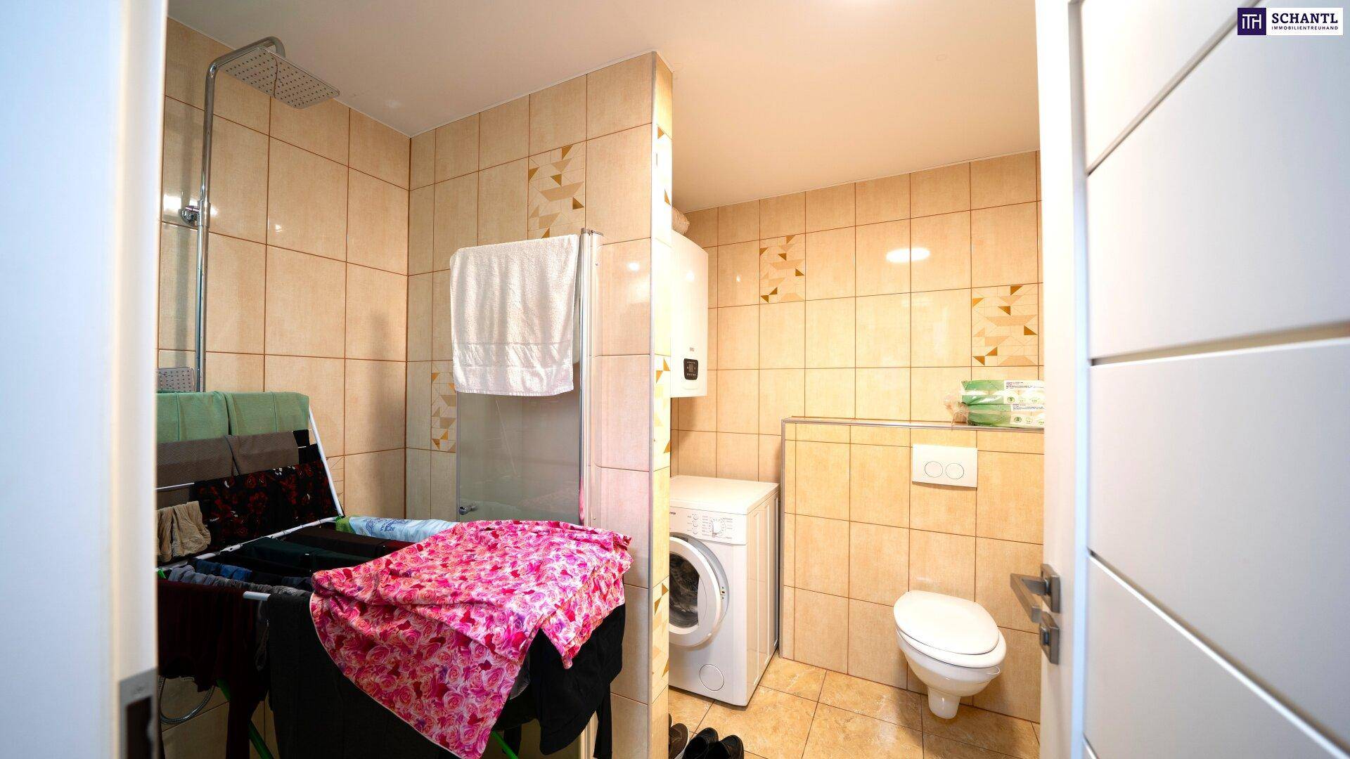 Funktionales Badezimmer mit Dusche, Waschmaschine und Toilette, komplett gefliest.