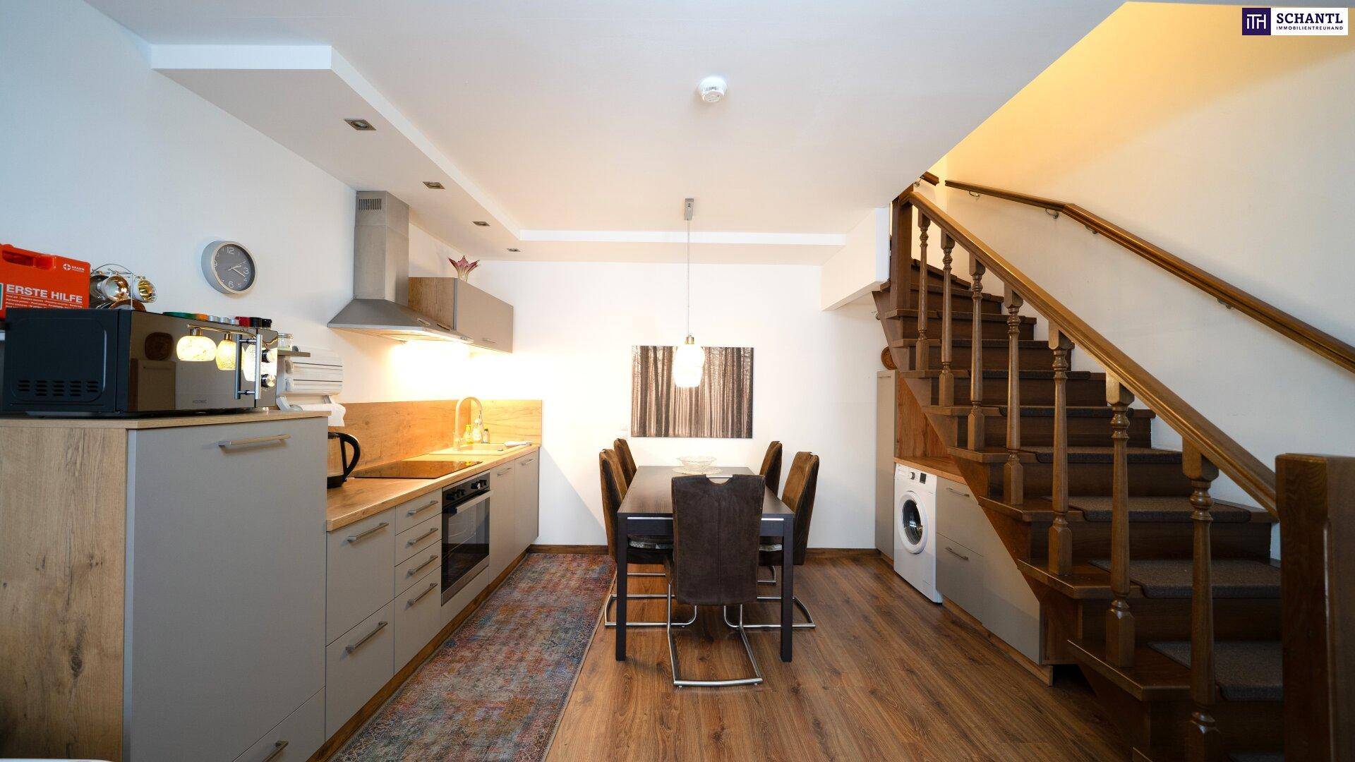 Moderne offene Küche mit Essbereich und Holztreppe, die in die obere Etage führt.