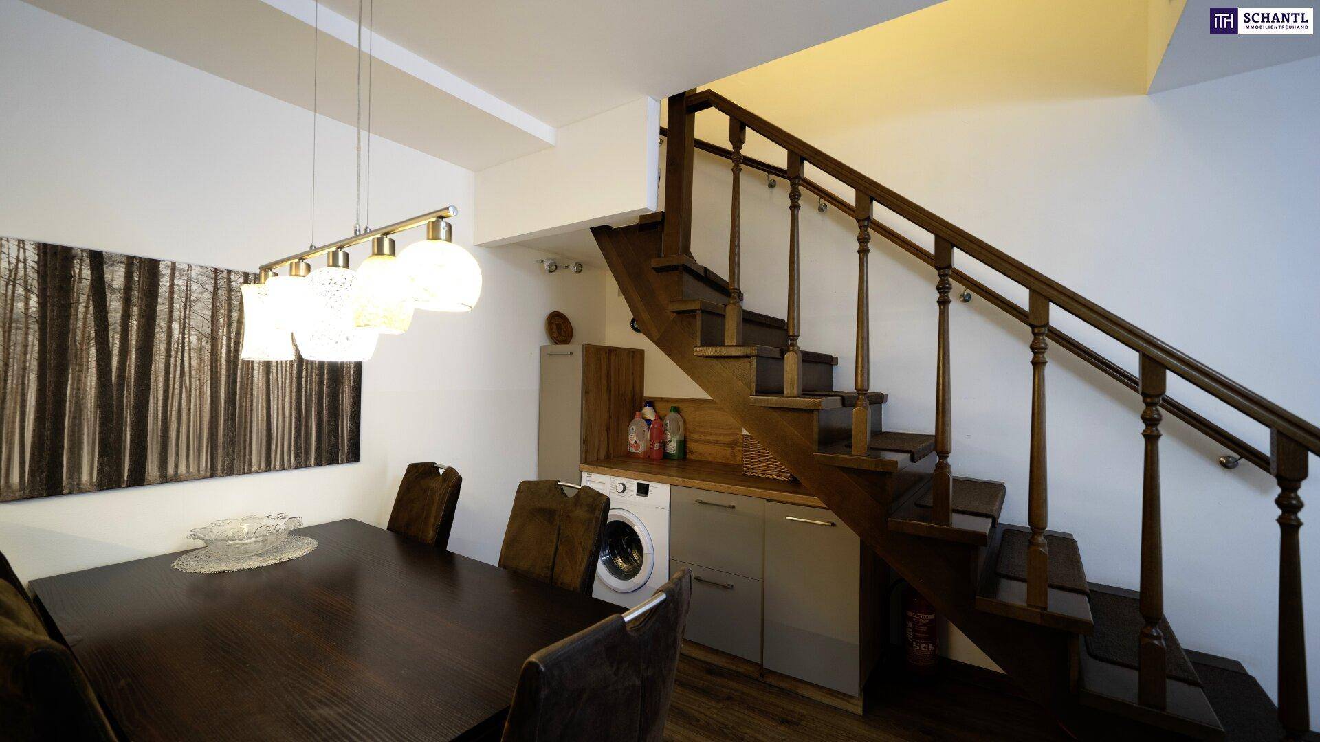 Gemütlicher Essbereich mit Holztisch und Stühlen, direkt neben der Treppe mit integrierter Waschmaschine.
