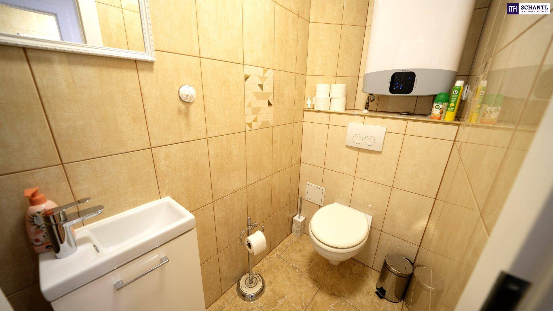 Kleines WC mit Toilette, Handwaschbecken und Wandboiler in beigefliestem Raum.